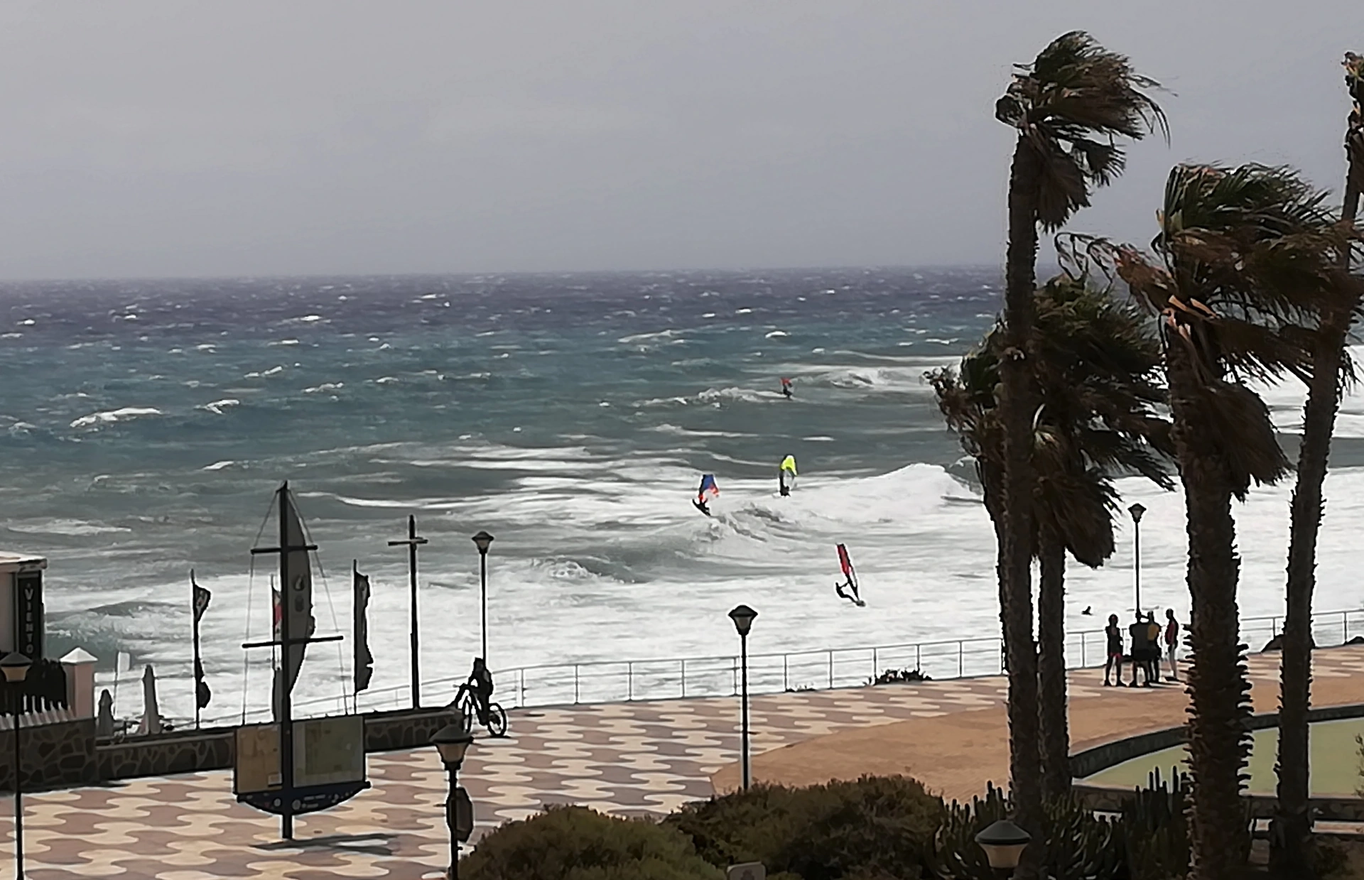 Paseo de Pozo Izquierdo con palmeras y windsurfistas en la bahía
