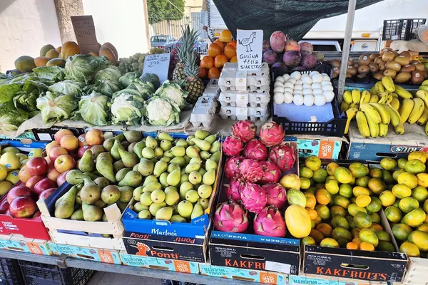 Puesto de fruta y verdura en el mercadillo de Vecindario, con peras, pitayas, manzanas, plátanos, coliflores y huevos